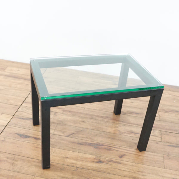1. Crate & Barrel contemporary end table with a minimalist wood frame and clear glass top on a wood floor.  