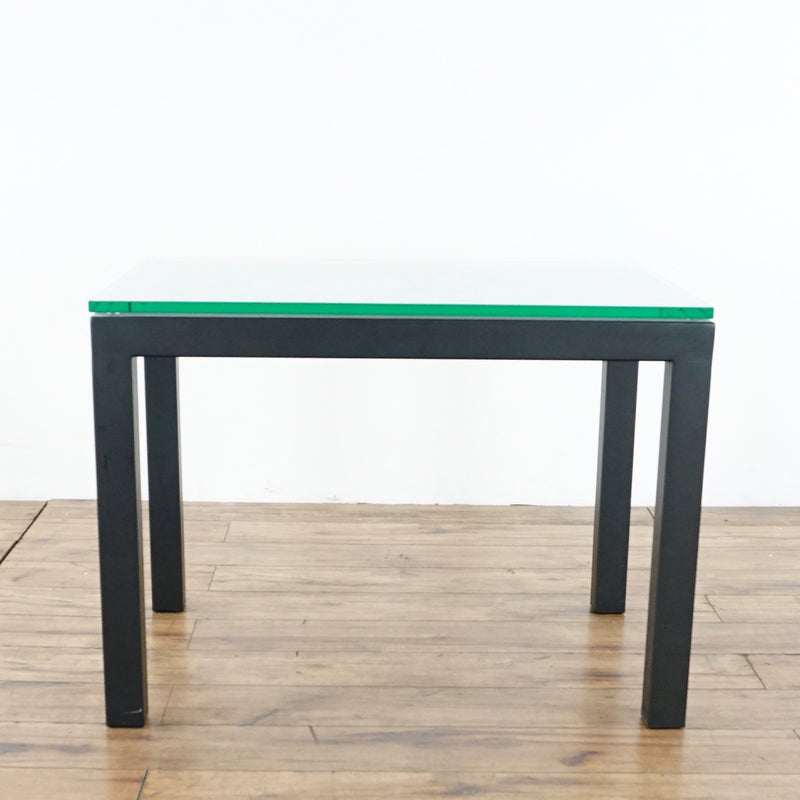 2. Modern end table by Crate & Barrel featuring a glass surface and sleek, dark wood legs, side view.  