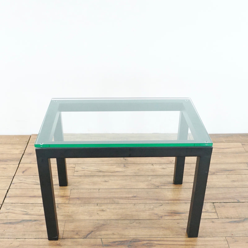 3. Rectangular glass-top end table with black wood frame, Crate & Barrel brand, shown from above.