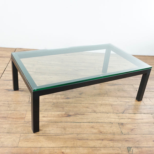 1. Crate & Barrel coffee table with a wood frame and clear glass top, shown from an angled view.