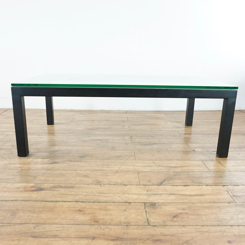 3. Side view of a Crate & Barrel coffee table with wood frame and glass top, for modern living spaces.