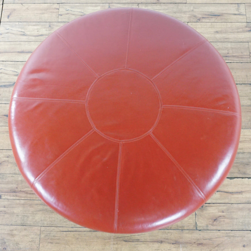 3. Top view of a circular custom red leather ottoman by Reperch, featuring segment stitching.