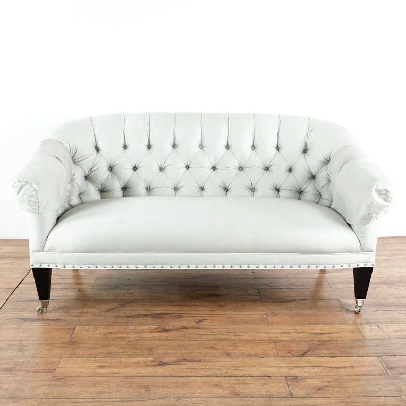 1. Light gray Reperch sofa with button tufted back, nailhead trim, and wood legs with casters on a wood floor.  
