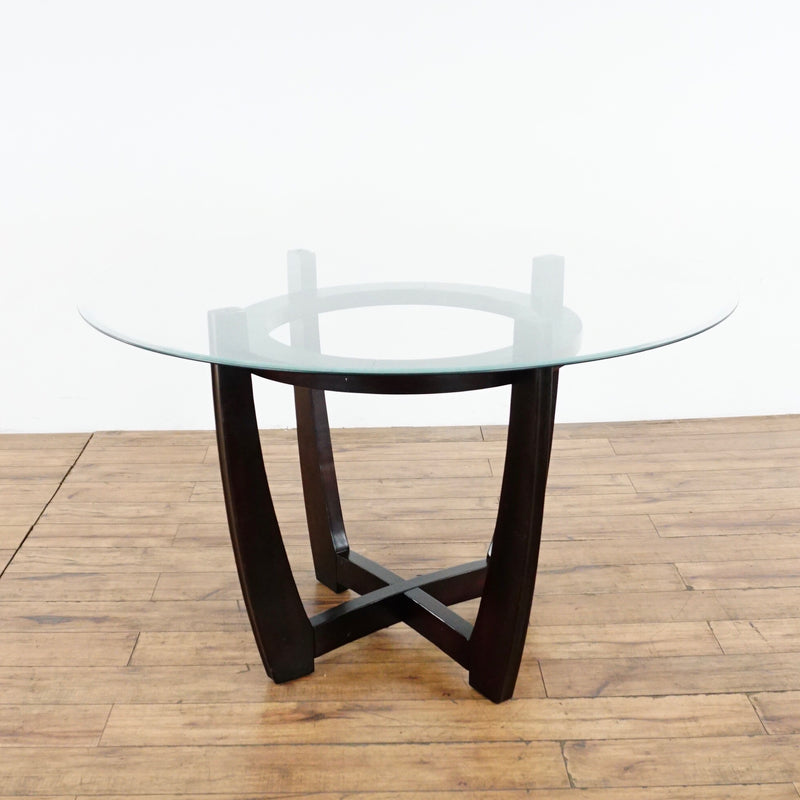 2. Side view of a round glass dining table by Ethan Allen, featuring curved dark wood legs in Mid Century style.