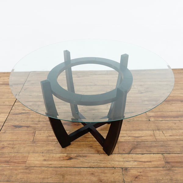 1. Mid Century Ethan Allen dining table with a round glass top and dark sculptural wooden base on wood floor.