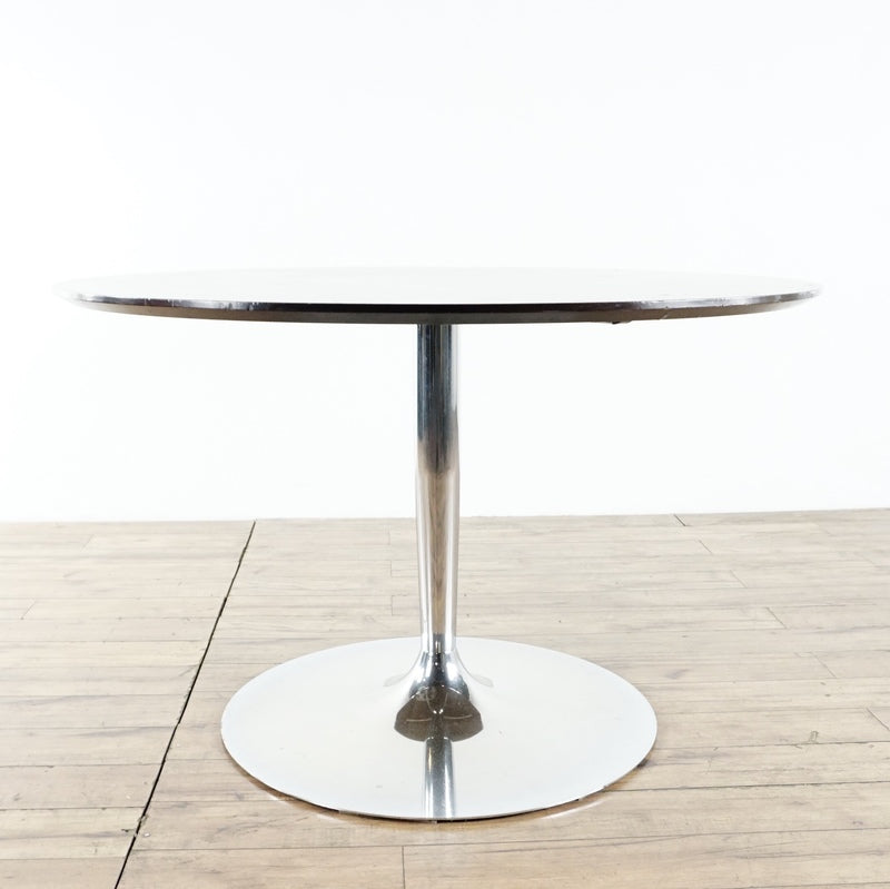 2. Modern Calligaris round dining table with chrome pedestal base and dark wood top, shown on wood flooring.