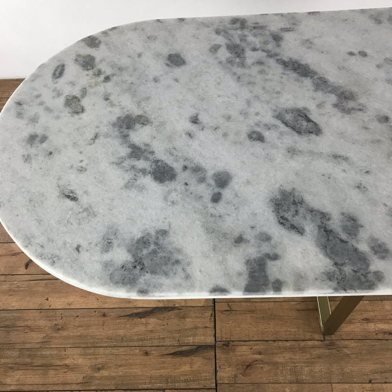3. Detail of the white and grey marble tabletop with rounded edges and visible brass support beneath.