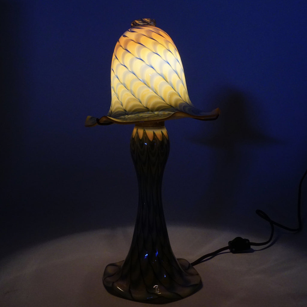 3. Artisan Reperch glass lamp with bell shade illuminated in a dark setting, accentuating vibrant patterns and curves.