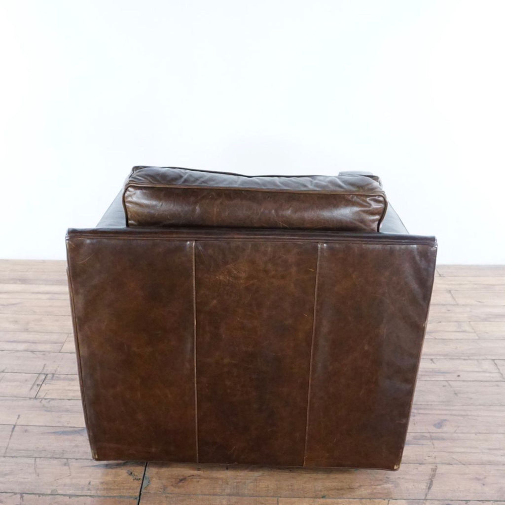 3. Rear angle of a Crate & Barrel leather chair, showing smooth, stitched back panel and cushioned headrest area.