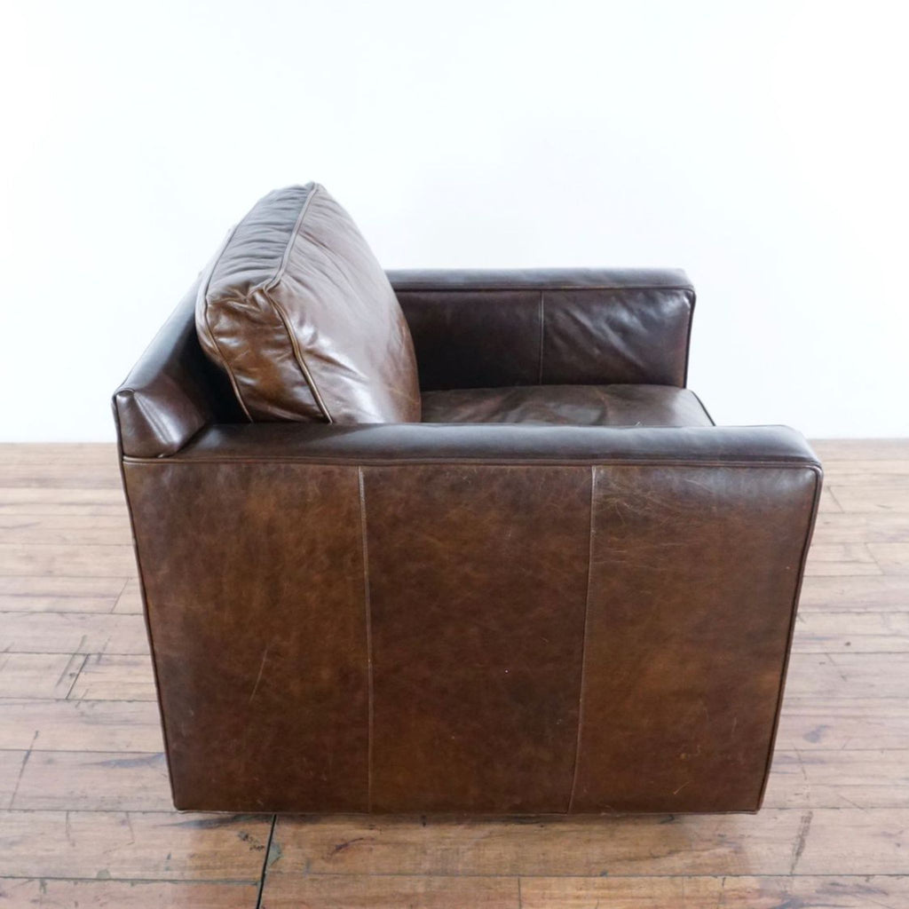 2. Side profile of a Crate & Barrel armchair, featuring dark brown leather upholstery and straight, modern lines.