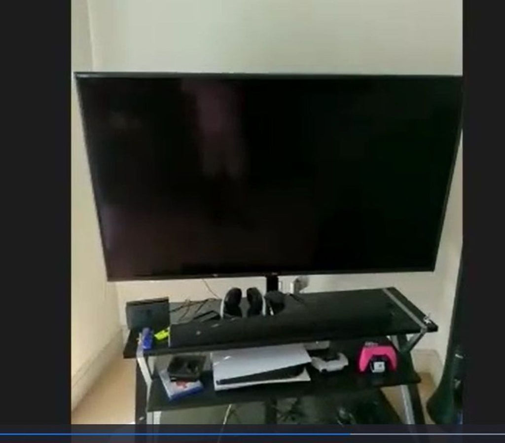 LG flat-screen TV displayed on a stand, surrounded by gaming accessories, in a cozy room setting.