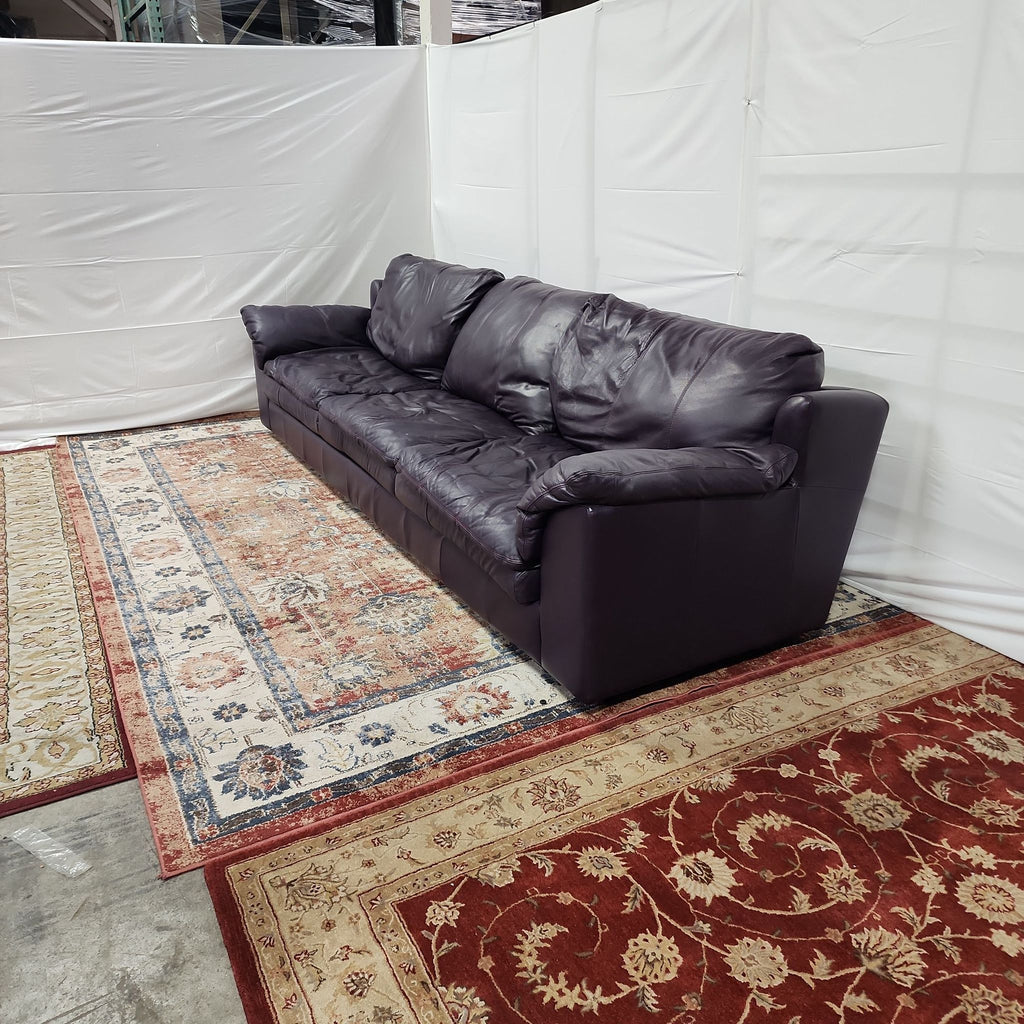 a black leather couch in a room with a white wall.