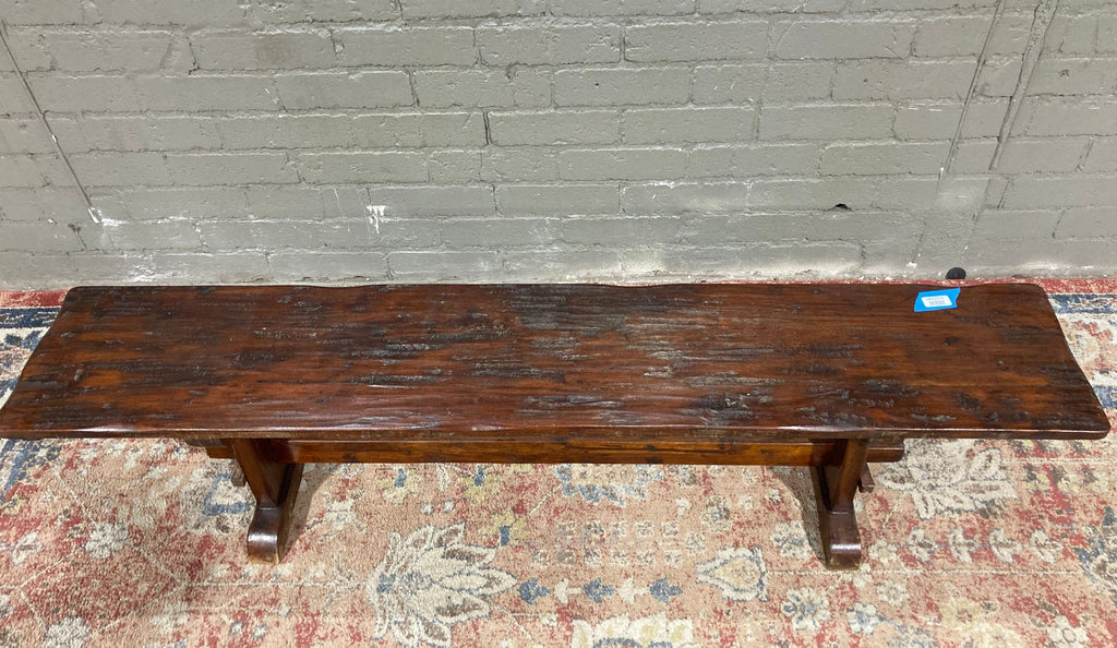 a wooden bench sitting on a brick floor 