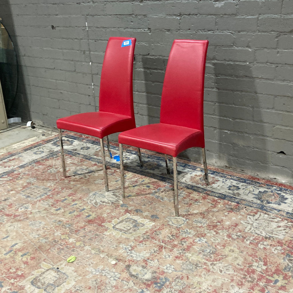 two red chairs sitting on a brick wall 