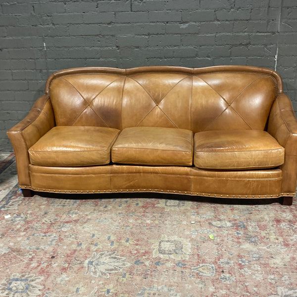 a brown leather couch sitting on a brick floor 