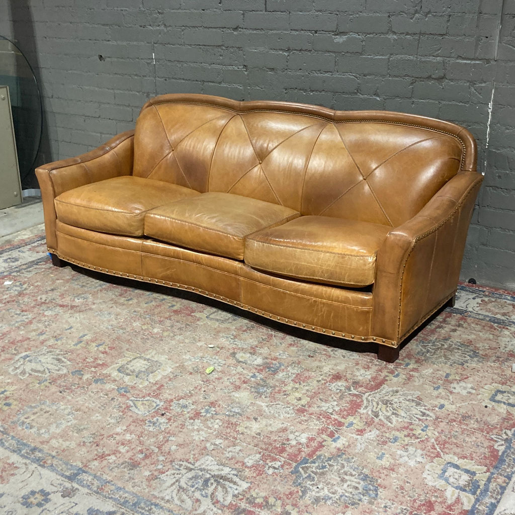 a brown couch sitting on a brick floor 