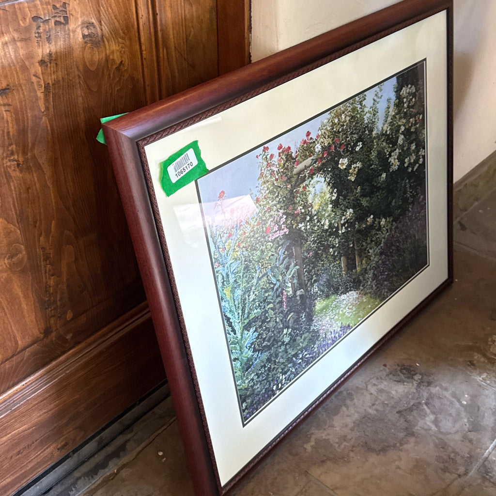 3. Side view of Reperch framed garden scene painting, flowers and archway, leaning near a wooden door.