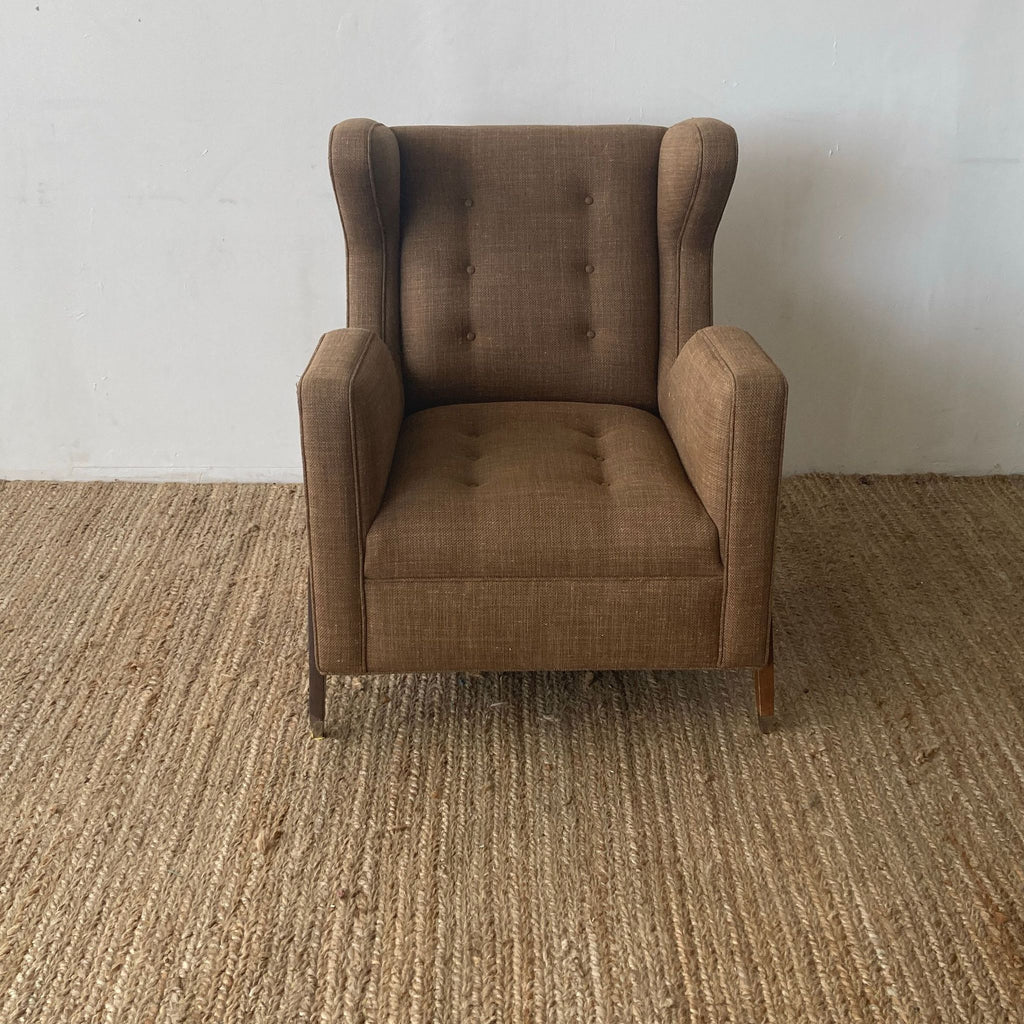 Mid-century modern wingback chair with button-tufted brown upholstery and angled legs.
