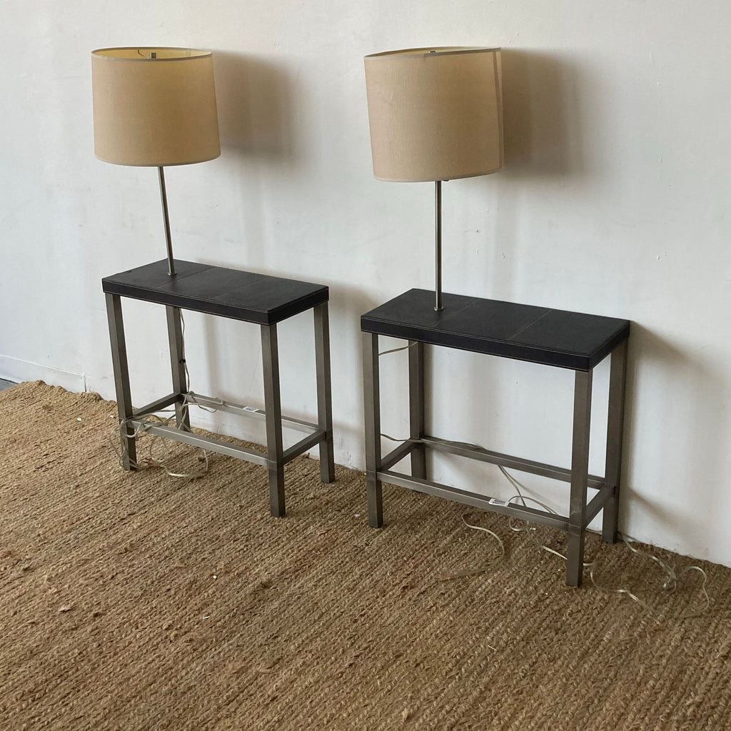 Two tables by a wall, each with a tall lamp and beige shade.