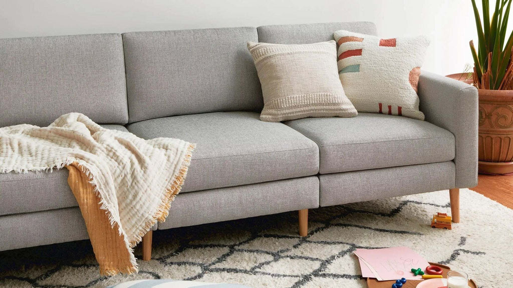 Gray Burrow Nomad sofa with pillows and blanket, showcasing a cozy living space.