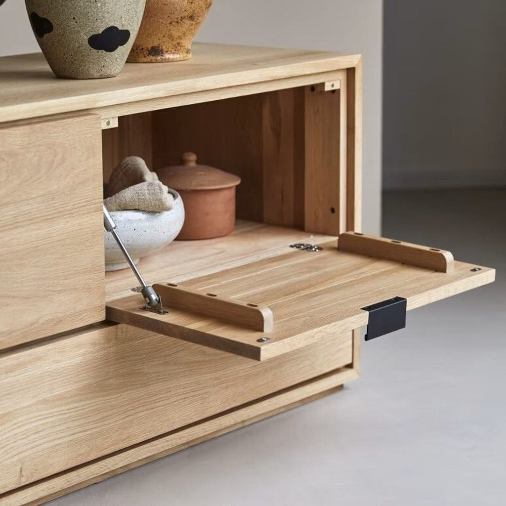 3. Close-up of Tikamoon entertainment center’s open compartment with a drop-down door housing bowls and pottery.