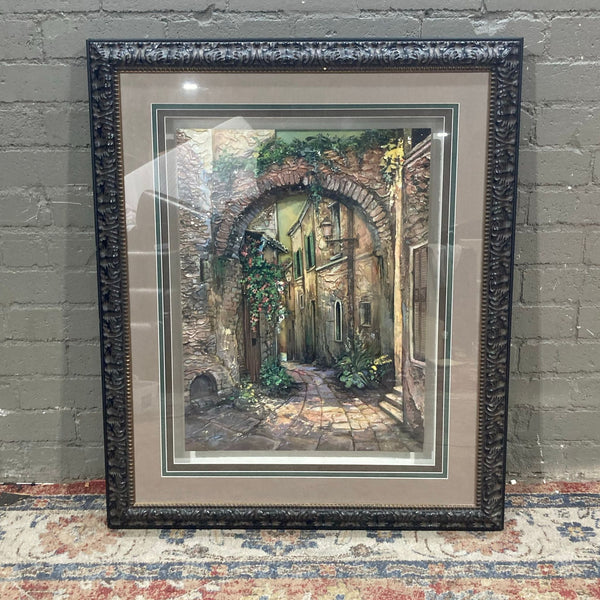 1. Framed Reperch art piece featuring a rustic alleyway under a stone arch, with lush greenery accents, 40x4x49.