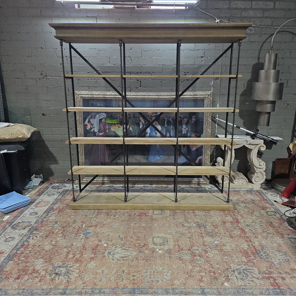 1. Restoration Hardware bookshelf with wood shelves and black metal frame, shown against a brick wall in an industrial room.