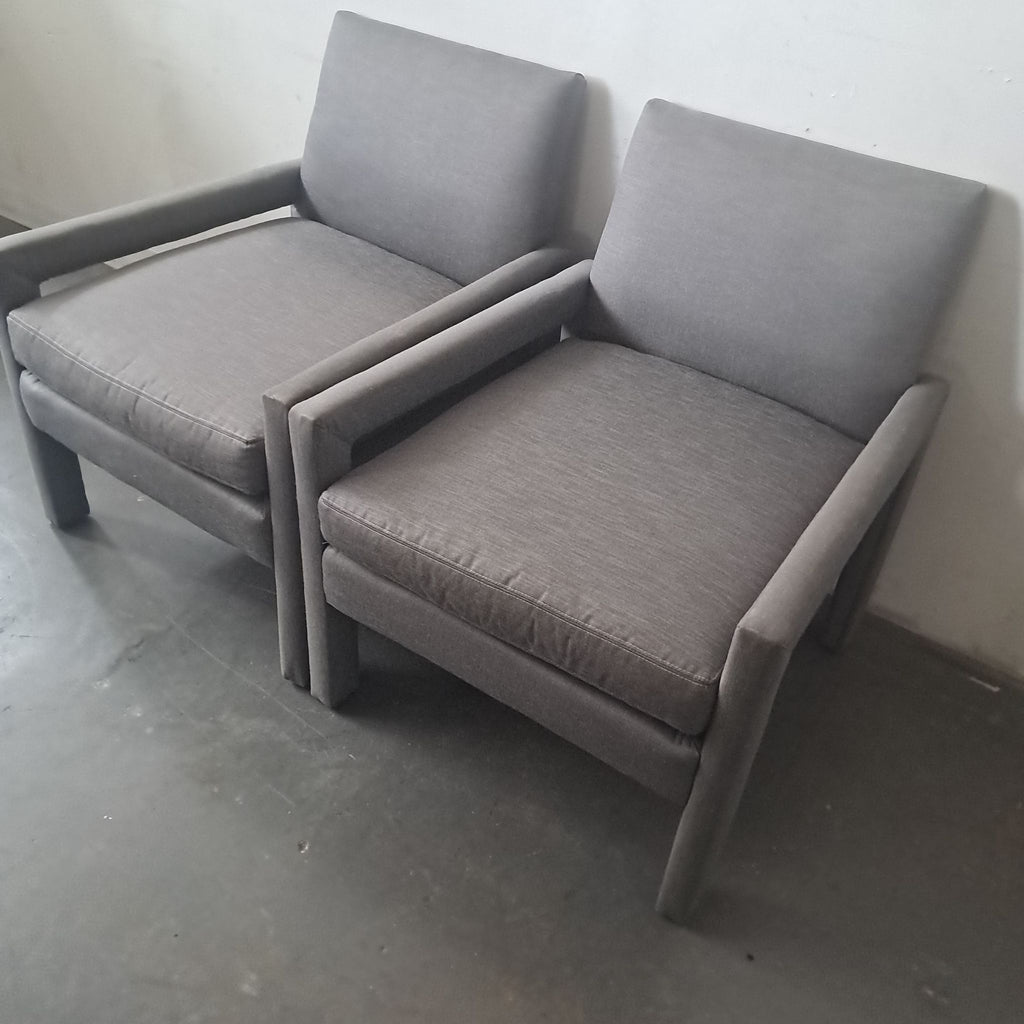 2. Two modern grey Jayson Home Collection lounge chairs angled together on a concrete floor.