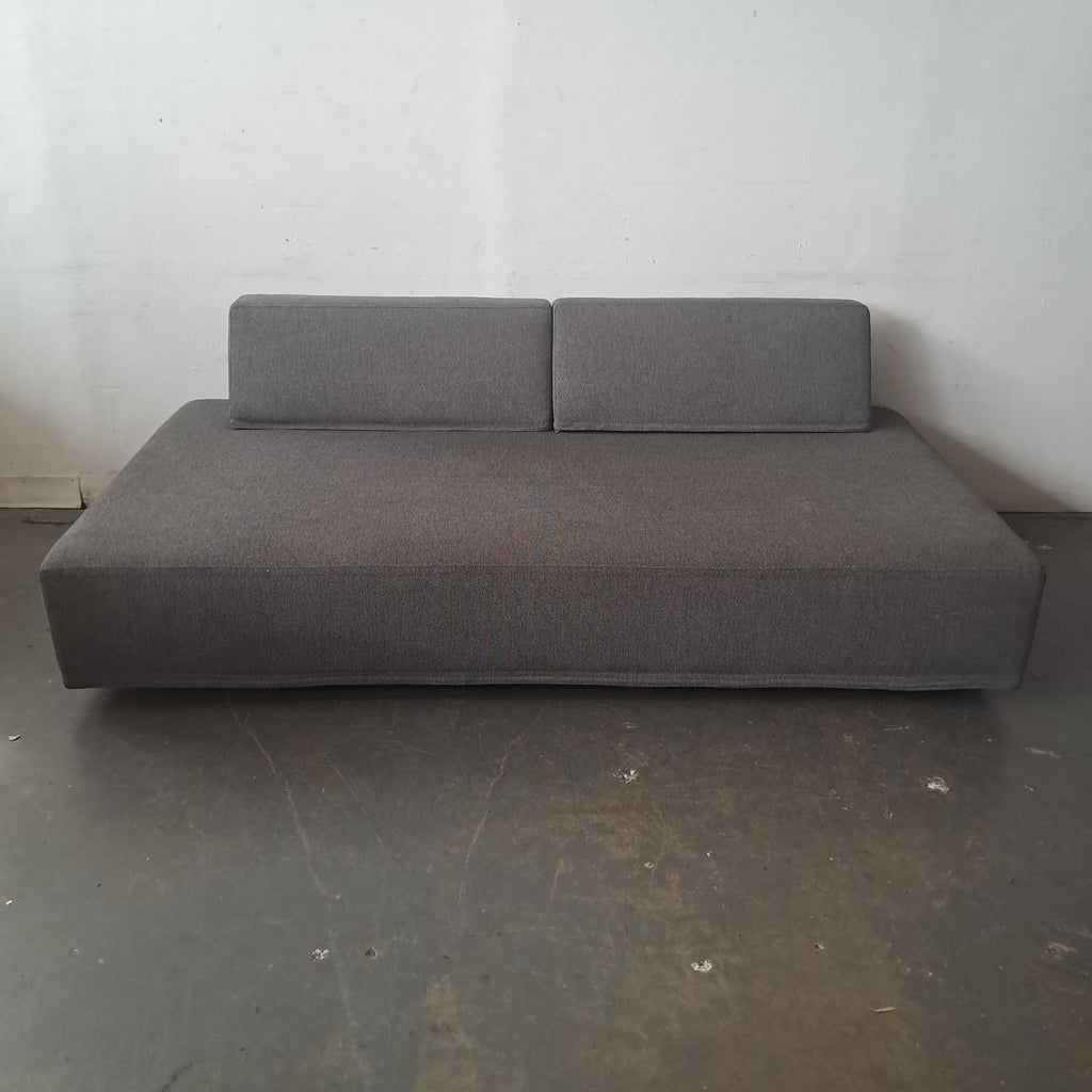 1. Minimalist gray Eilersen sofa with low profile and two rectangular backrests, shown against a plain wall.