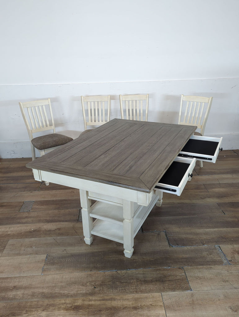 2. Ashley Furniture dining table with open side drawers, surrounded by four slatted-back chairs.