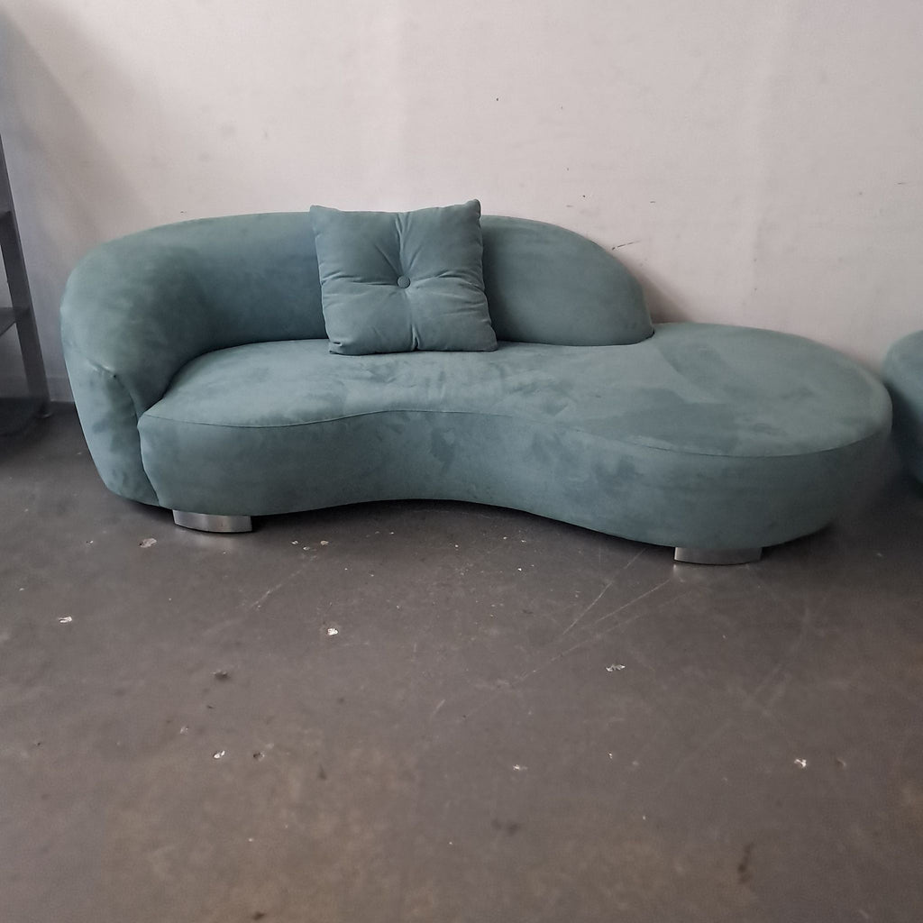 2. Close-up of a single teal curved sectional sofa from Lazar Industries, featuring a tufted pillow and round metal legs.