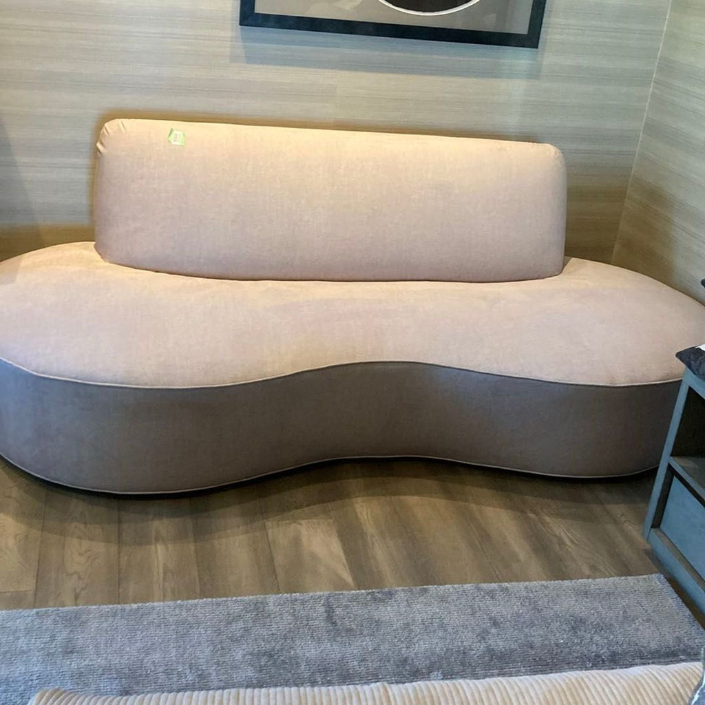Modern beige lounge sofa featuring a unique curved design and cushioned seat for comfort and style.