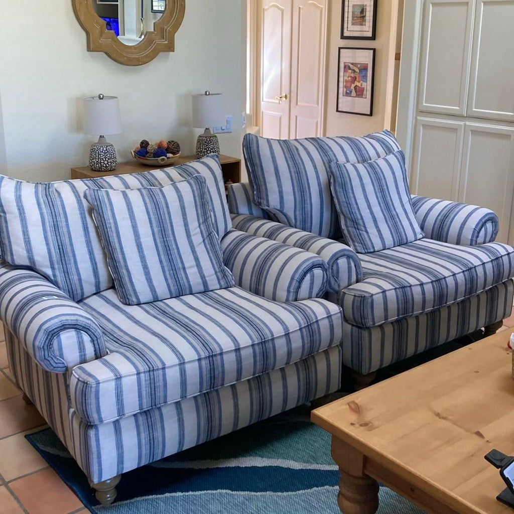 Set of two oversized lounge chairs in striped fabric and wooden legs, offering cozy seating for any lounge area.