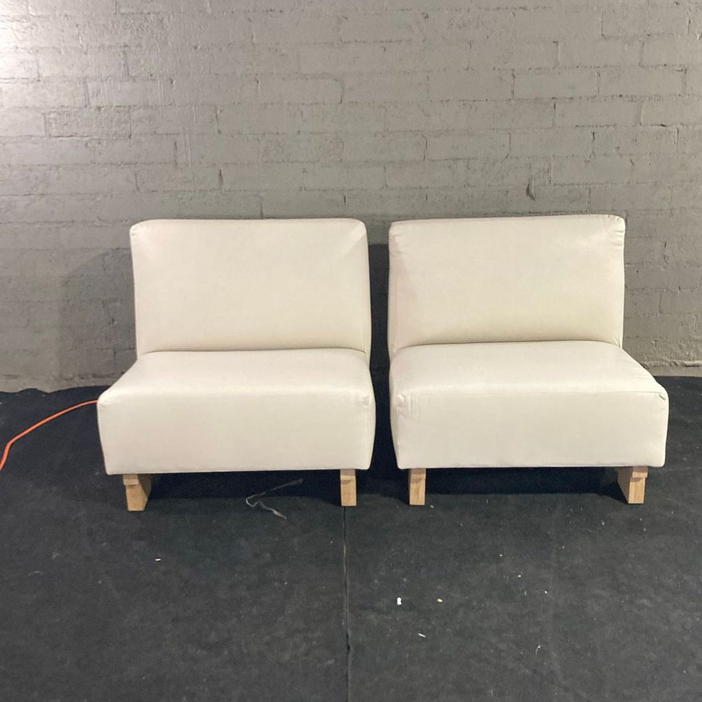2. Front view of two cream upholstered lounge chairs on wooden legs, placed side by side.  