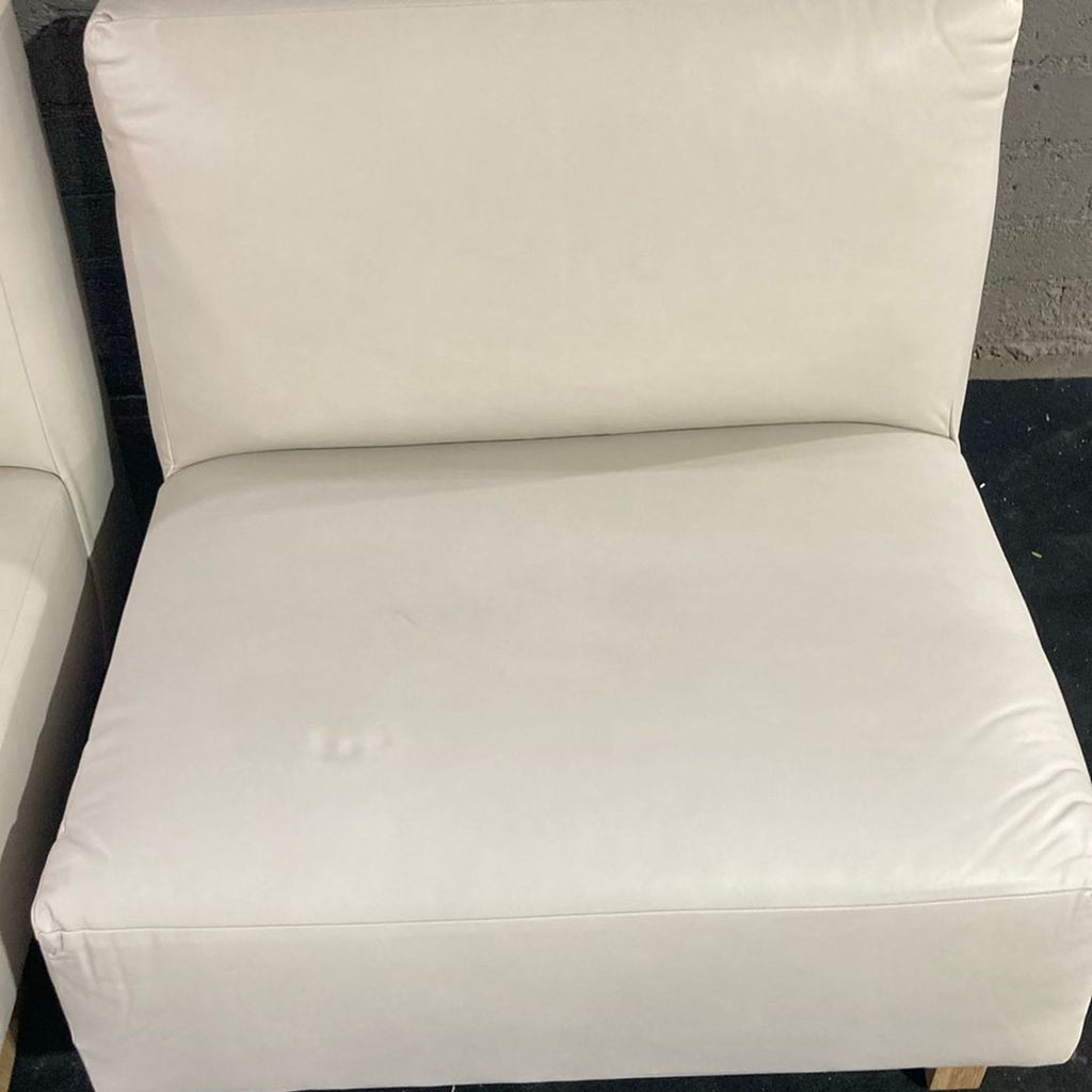 3. Close-up of a single armless cream lounge chair with wooden legs, showing the seat and backrest.