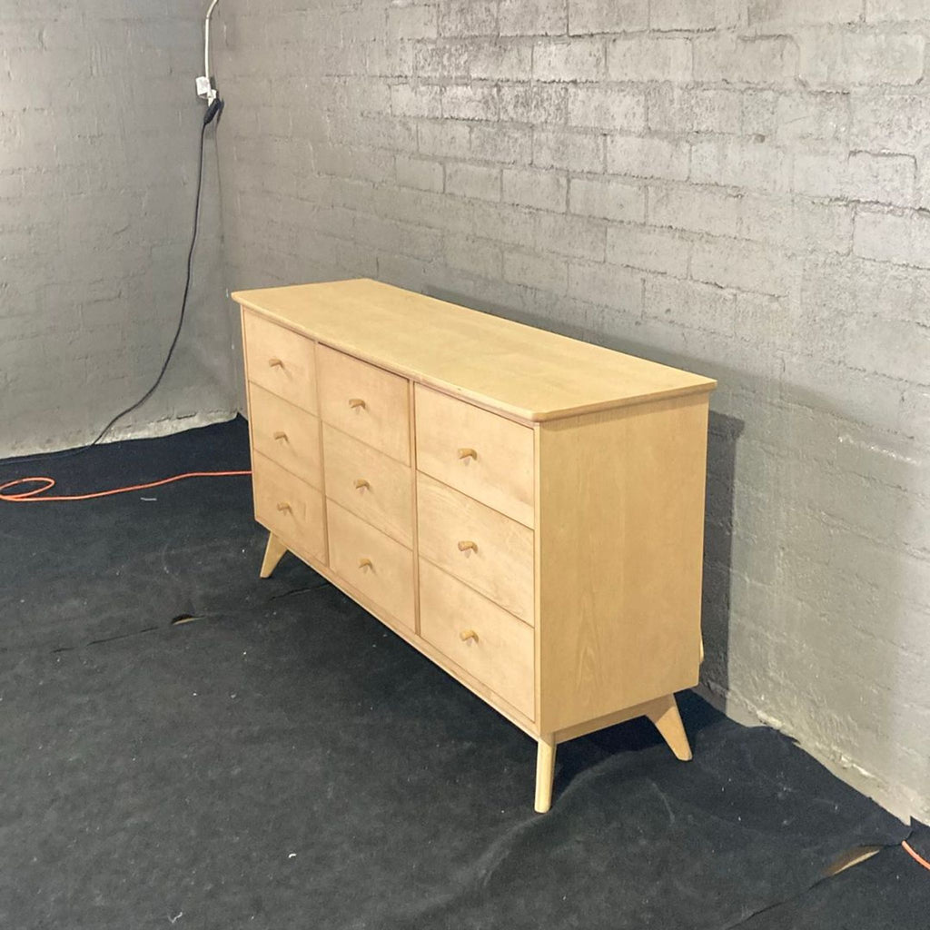 2. Side angle view of a Living Spaces natural wood dresser with splayed legs and nine spacious drawers.  