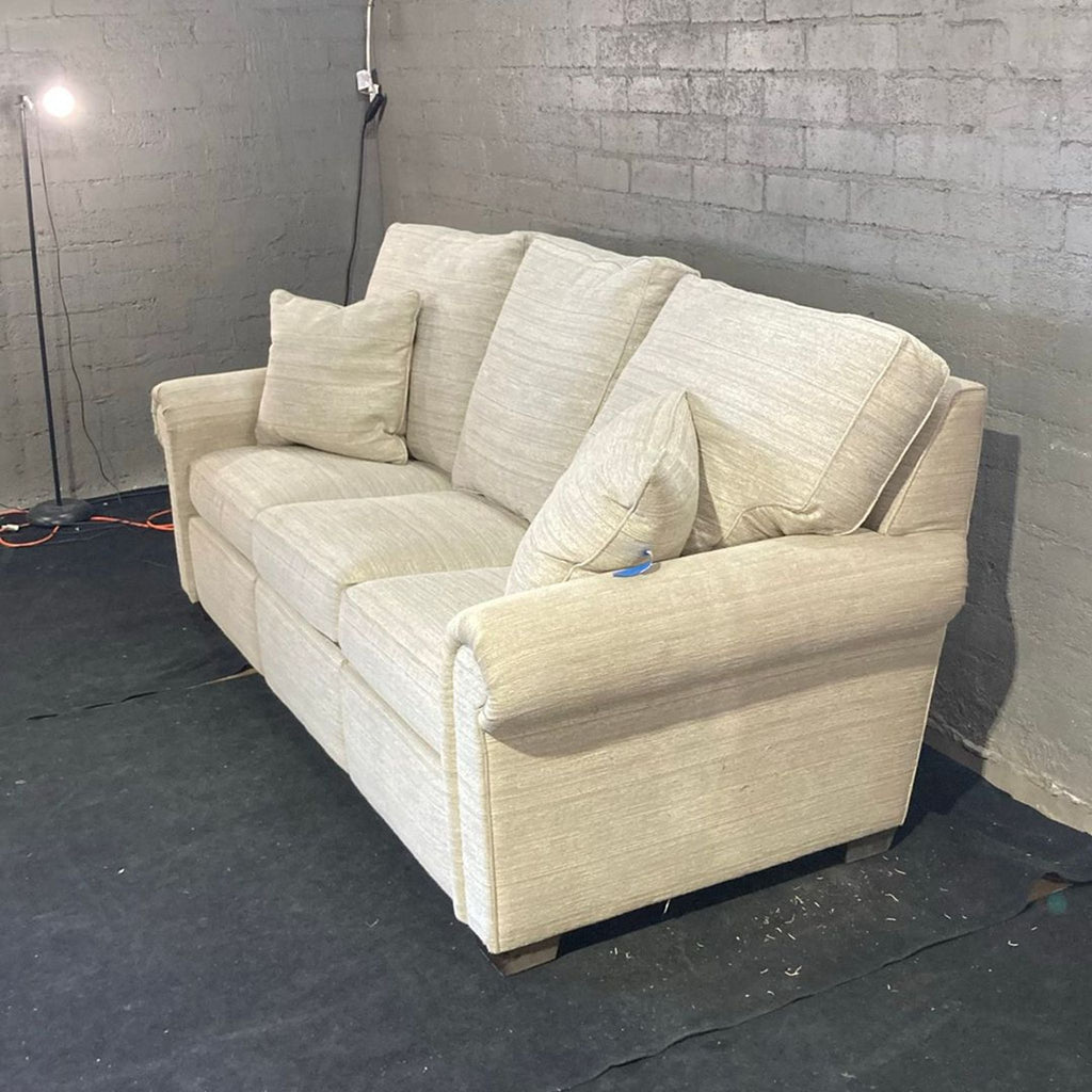 Light beige Stickley 3-seater sofa, cushioned seats and back, two throw pillows, classic rolled arm style.