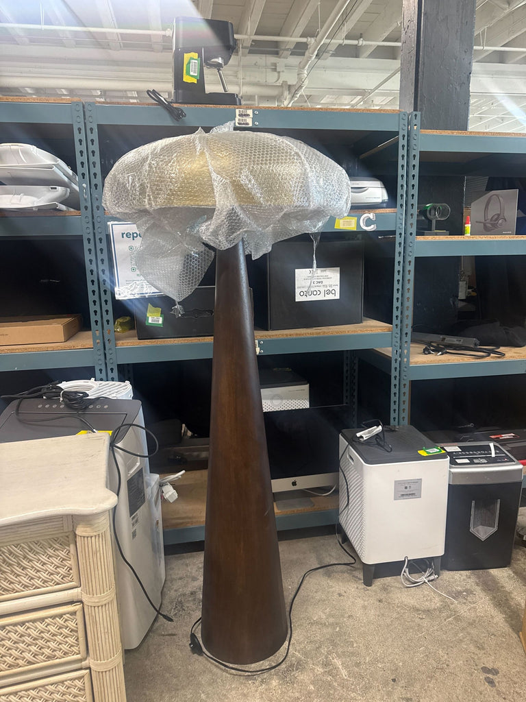 3. Lulu and Georgia floor lamp with a brass dome shade wrapped in bubble wrap, shown in a storage area.