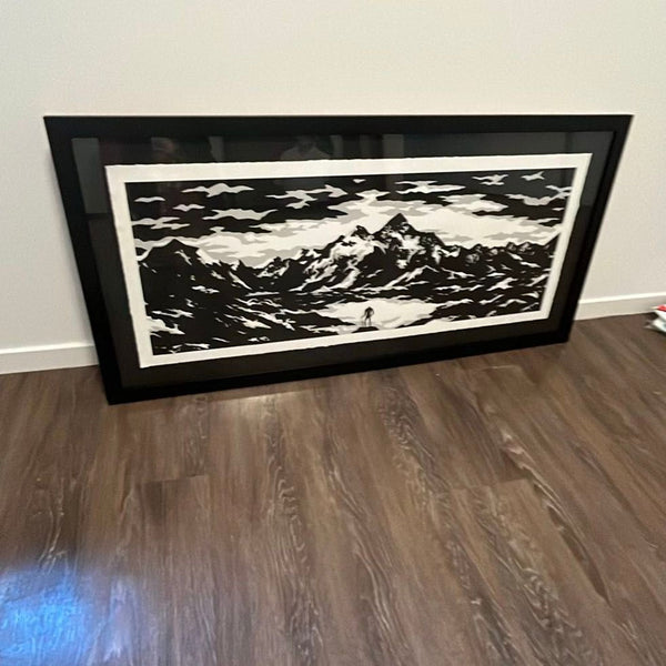Black and white mountain print with a lone figure, framed in black for modern home or office decor.