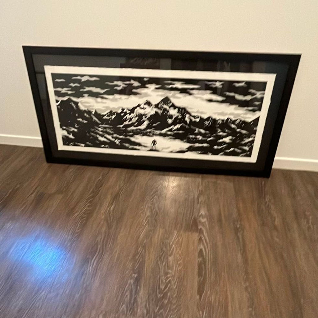 Striking black and white mountain scene print, single person in foreground, set in sleek black frame.