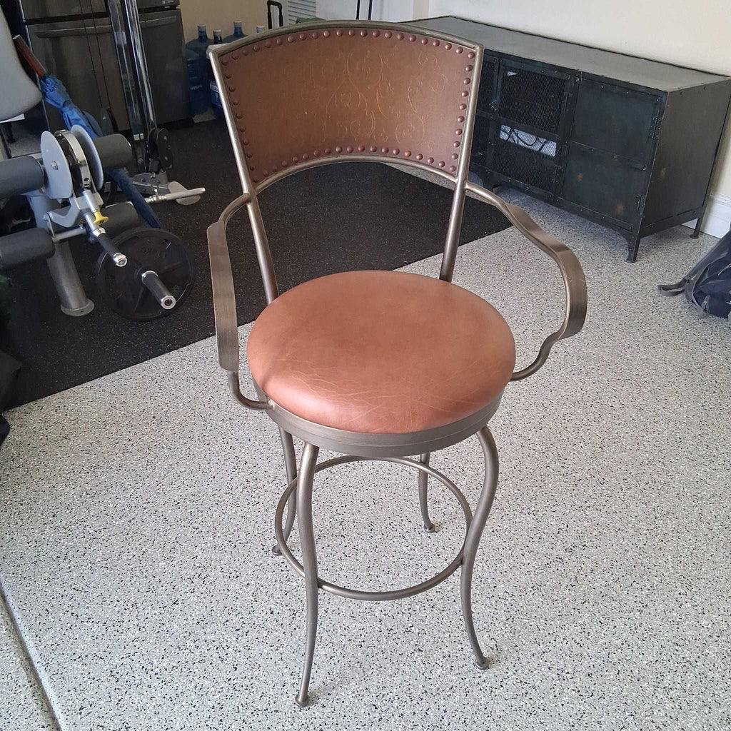 Brown leather Artistica Home dining chair with metal frame, armrests, and swivel seat.