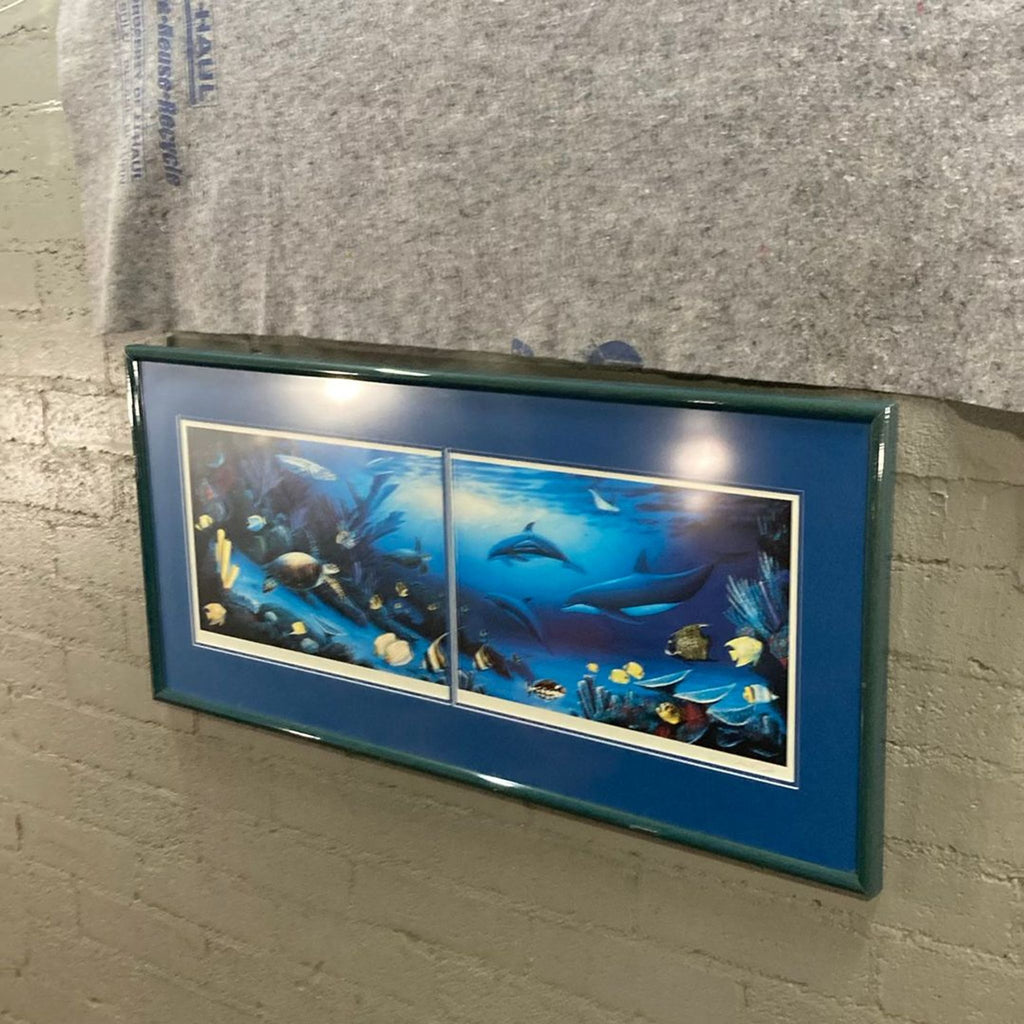 Double-matted marine life art print in a blue frame, showing lively dolphins, turtle, and vivid tropical fish underwater.