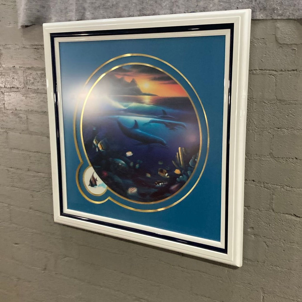Vibrant underwater ocean scene print featuring dolphins, tropical fish, and sunset colors in a round, gold-accented frame.