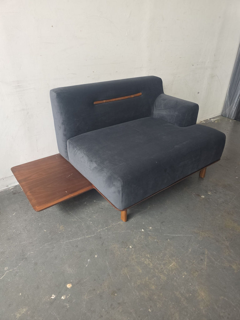 Compact blue sectional sofa featuring a unique wood accent on the backrest and a built-in side table.