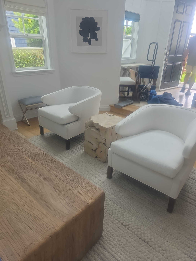 Two stylish white lounge chairs featuring soft upholstery and sturdy dark legs, perfect for a living area.  
