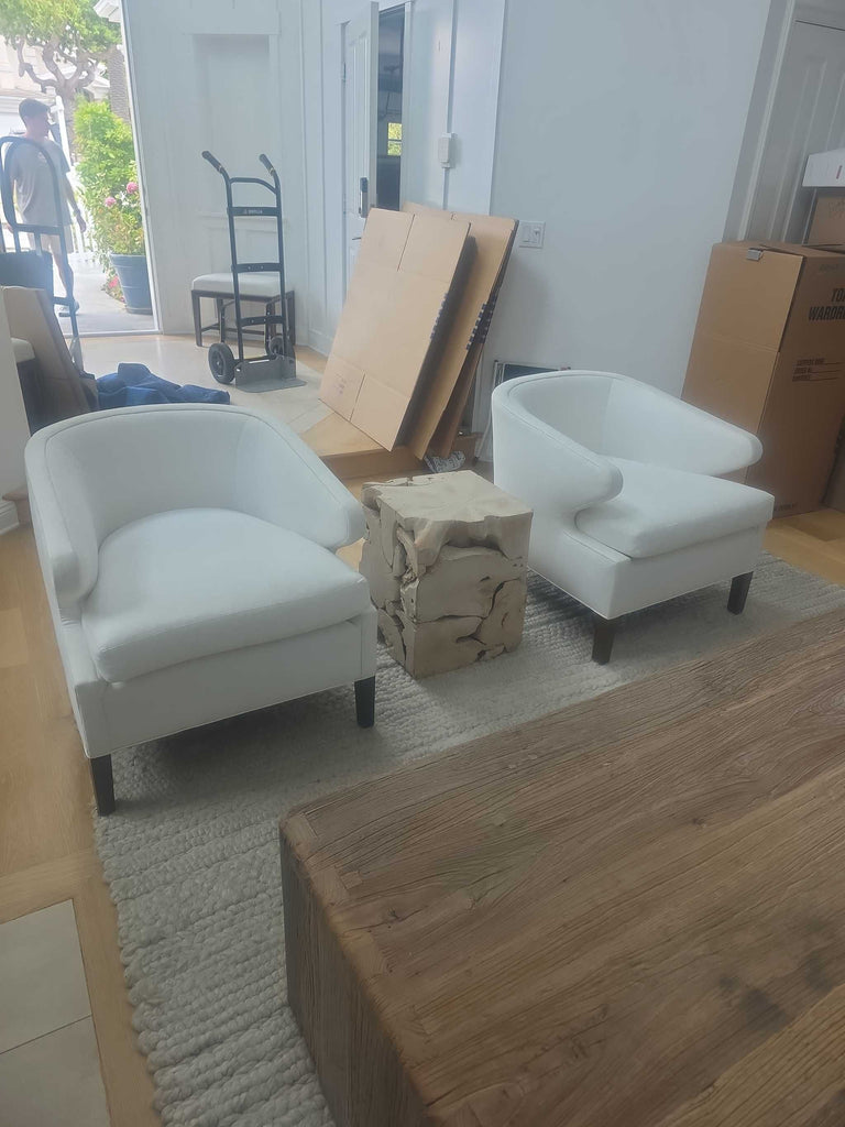 Pair of modern white lounge chairs with rounded arms, plush cushions, and dark contrasting legs.  