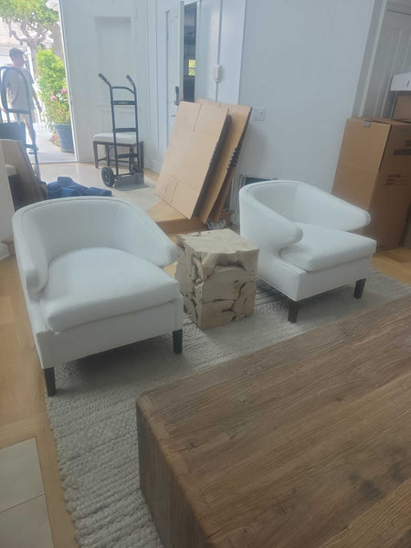 Pair of modern white lounge chairs with rounded arms, plush cushions, and dark contrasting legs.  