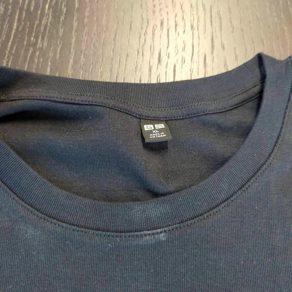 3. Neckline and tag of a black Uniqlo women's T-shirt in size XL, highlighting brand and size details.