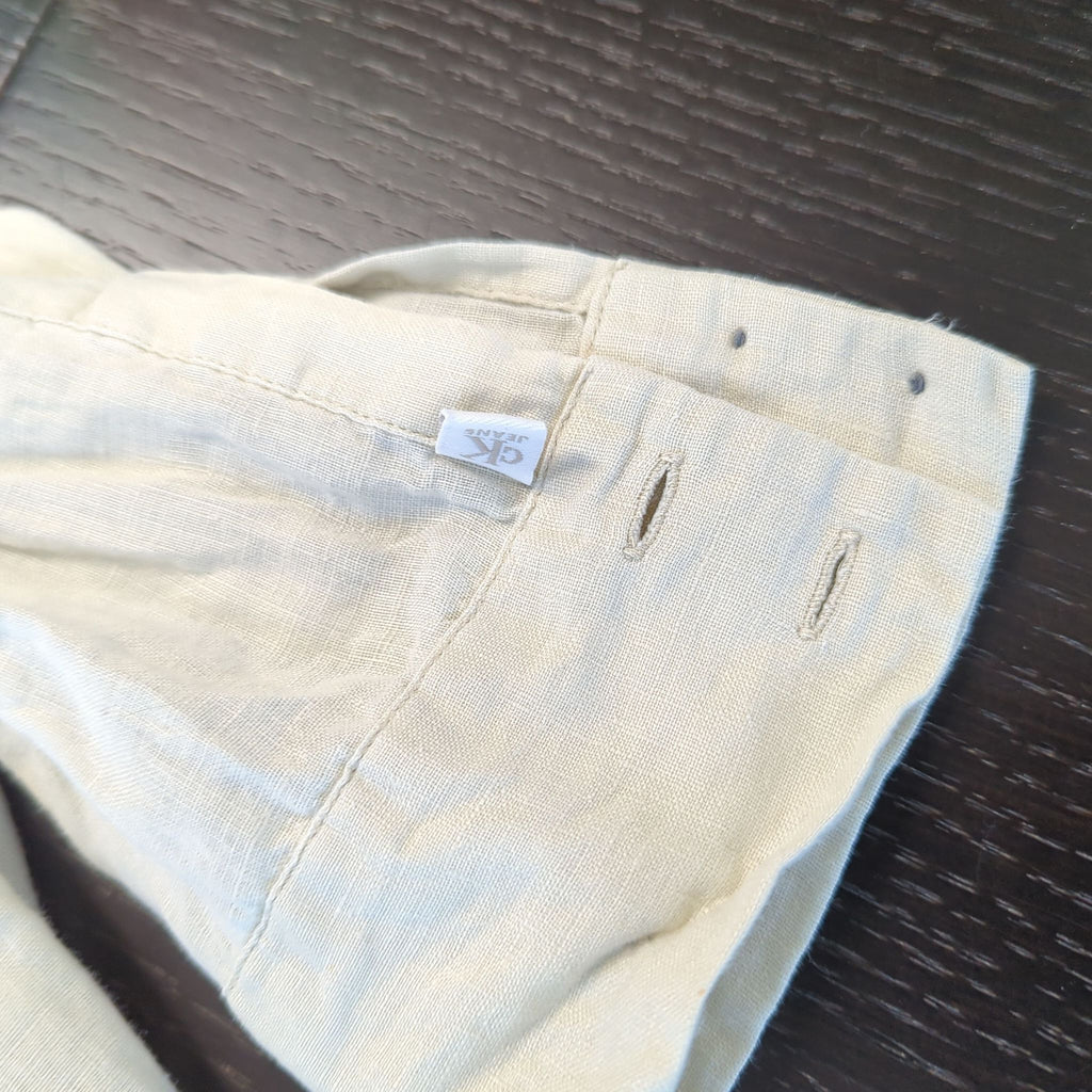 3. Calvin Klein Jeans branded tag on the cuff of a light beige women’s long-sleeve shirt.