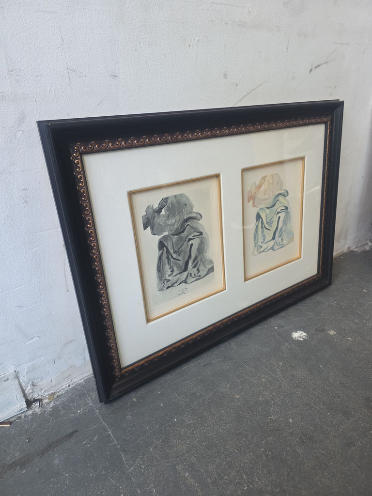 3. Angled view of a framed pair of figure drawings, one grayscale and one colored, on a gray concrete floor.